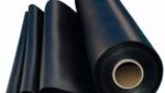 Um rolo de borracha nitrílica disposto em camadas, com acabamento liso e diâmetro uniforme. O rolo é da cor preta e está pronto para uso em aplicações industriais e automotivas, como fabricação de vedações, juntas e outros componentes resistentes.