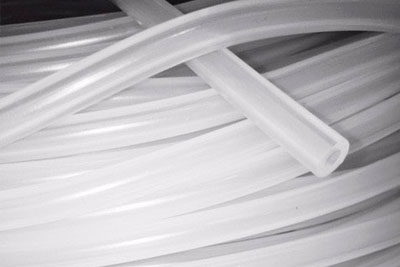 Um conjunto de mangueiras de silicone em posições cruzadas. As mangueiras são de cor branca translúcida e têm um formato cilíndrico liso. A disposição destaca a flexibilidade e a uniformidade do material, que é ideal para aplicações em ambientes industriais e de laboratório.