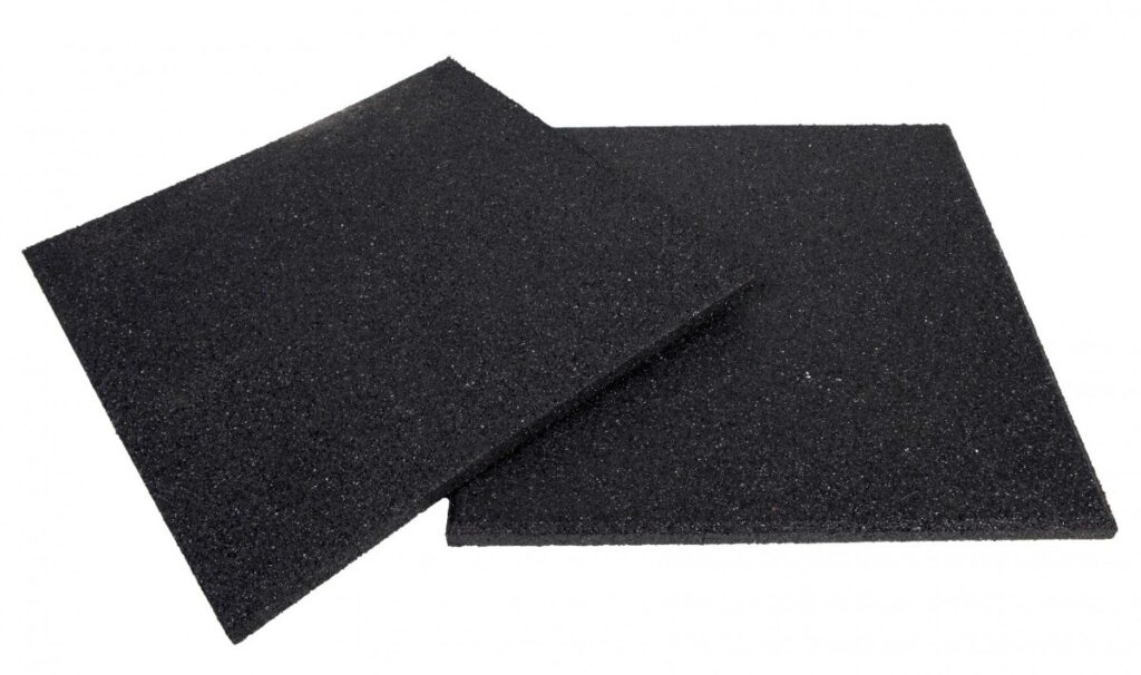 Imagem de duas peças de piso emborrachado, destacando a textura rugosa e a coloração preta. As placas são ideais para ambientes de treinamento, oferecendo suporte e conforto durante exercícios de alta intensidade.