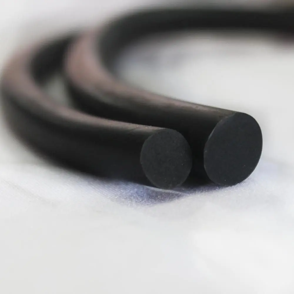 Dois cordões de borracha pretos, de diferentes diâmetros, estão entrelaçados e repousam sobre uma superfície branca, apresentando um aspecto macio e flexível.