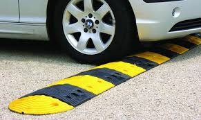 "Lombada de borracha amarela instalada em um estacionamento, utilizada para reduzir a velocidade dos veículos e aumentar a segurança de pedestres e motoristas na área."