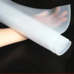 Pessoa segurando um rolo de revestimento de borracha, mostrando o material branco e flexível, utilizado em aplicações industriais para proteção e vedação.