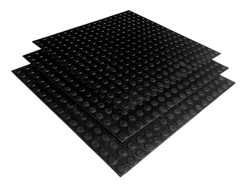Três placas de piso bolha pastilhado de cor preta, empilhadas uma sobre a outra, exibindo a textura de bolhas em toda a superfície, usadas para revestimento de áreas de circulação.