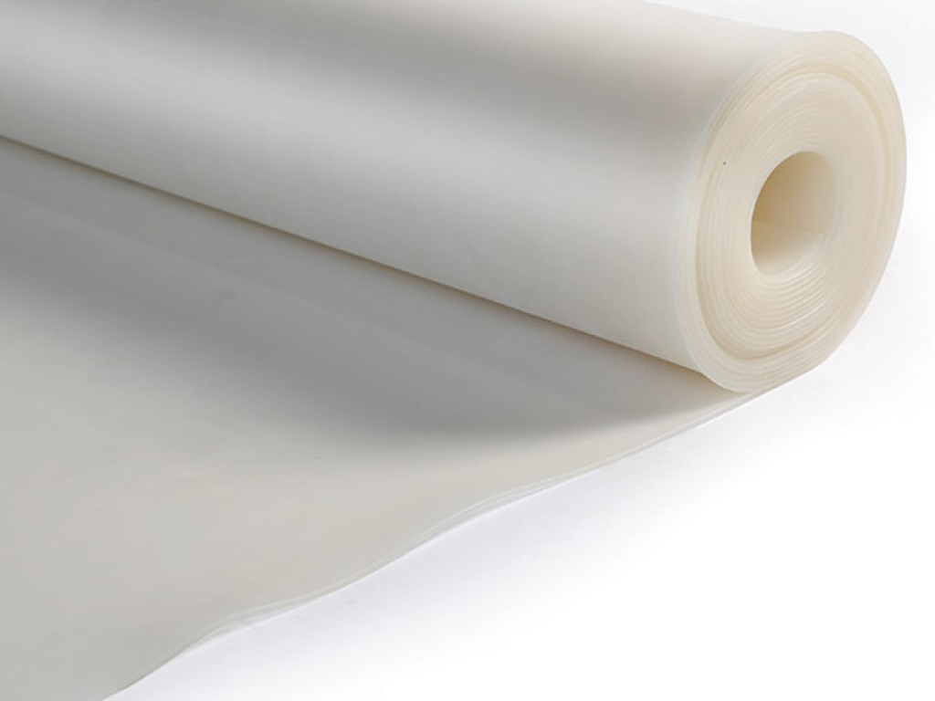 Um rolo de material de silicone de cor branca está parcialmente desenrolado, com uma extensão do material estendida sobre uma superfície branca. O fundo é também branco, criando uma composição limpa e minimalista.