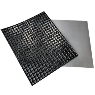 Imagem mostrando duas almofadas de borracha usadas para fins industriais ou de construção. Uma almofada tem uma superfície lisa e plana, enquanto a outra apresenta uma grade de saliências quadradas elevadas, provavelmente projetadas para maior aderência, absorção de vibração ou distribuição de carga. Ambas estão posicionadas sobre um fundo neutro, enfatizando sua textura e espessura.