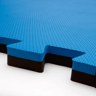 Imagem de uma peça de tatame de cor azul com espessura de 3cm, exibindo sua superfície com textura antiderrapante. A peça apresenta um encaixe com um sistema de trava nas bordas, facilitando a união com outras peças para formar um espaço de treino ou competição de artes marciais.