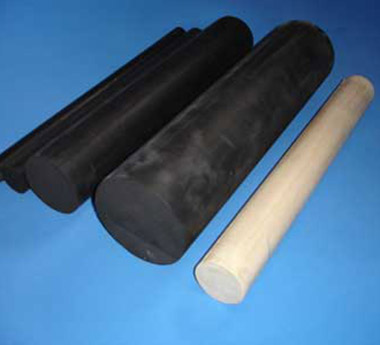 Três vedações cilíndricas de Neoprene pretas, com diâmetros diferentes, ao lado de uma peça cilíndrica clara de tom bege.Os tarugos têm formato semicircular com cantos arredondados e superfícies lisas, sugerindo itens de vedação flexíveis usados em câmaras de testes automotivos. Fundo azul sólido, iluminação uniforme e sem marcas ou textos.