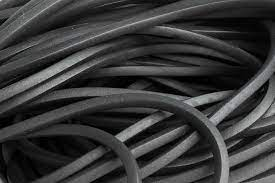 rançado de cabos ou fios pretos emaranhados, formando curvas e nós sobre fundo claro. A textura é áspera, com espirais e dobras destacadas, sugerindo um agregadO de fios elétricos ou cabos de maquinaria.