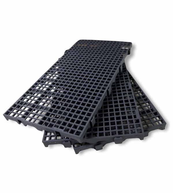 Três grelhas de piso de plástico preto empilhadas, com estrutura aberta em formato de grade, usadas como ralos ou plataformas modulares, com superfície retangular e encaixes na base para montagem.