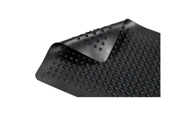 Imagem de um piso emborrachado preto com textura antiderrapante, apresentando pequenos relevos circulares. O material é flexível e projetado para oferecer segurança e conforto, ideal para ambientes como academias, vestiários ou áreas de treinamento. Sua superfície facilita a aderência, reduzindo riscos de escorregões.