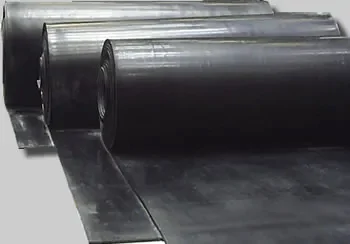 A imagem mostra rolos de lençol de borracha preta dispostos em sequência. O material parece resistente e flexível, ideal para uma variedade de aplicações industriais, como selos, juntas e revestimentos. 