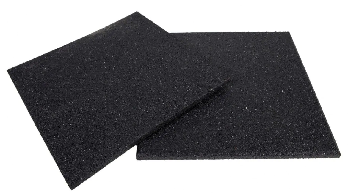 Imagem de duas peças de piso emborrachado, destacando a textura rugosa e a coloração preta. As placas são ideais para ambientes de treinamento, oferecendo suporte e conforto durante exercícios de alta intensidade.