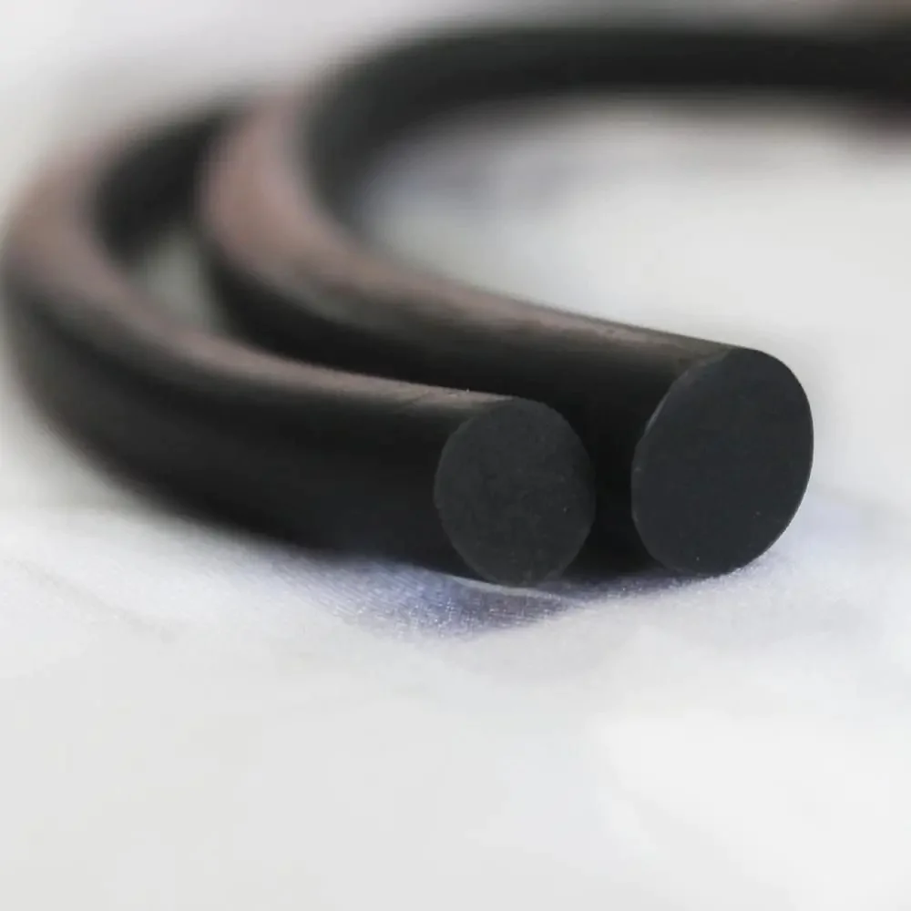 Dois cordões de borracha pretos, de diferentes diâmetros, estão entrelaçados e repousam sobre uma superfície branca, apresentando um aspecto macio e flexível.