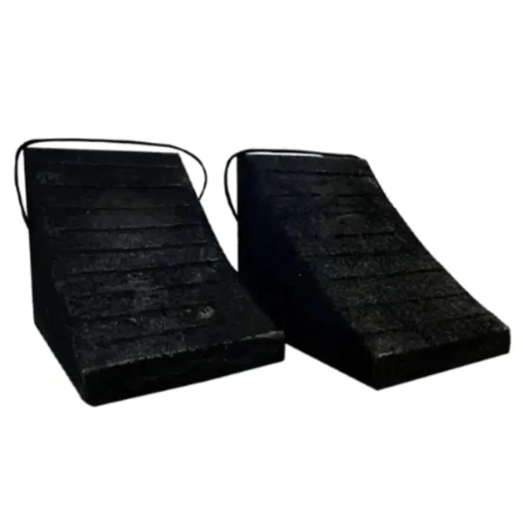 Par de calços de borracha preta com superfície estriada para melhor aderência e alças acopladas para fácil posicionamento. Projetados para impedir o movimento do veículo durante operações de estacionamento ou carregamento.