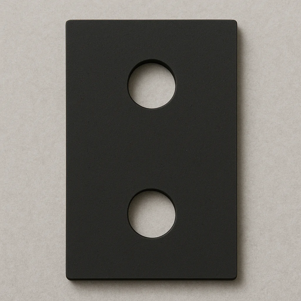 Imagem de uma placa de neoprene preta retangular, com duas cavidades circulares alinhadas verticalmente no centro. Essa peça é utilizada para isolamento, proteção ou absorção de vibrações em aplicações industriais, de manutenção ou equipamentos elétricos, contribuindo para maior durabilidade e segurança das instalações.