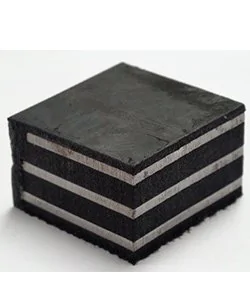 Imagem de uma peça de neoprene fretado, que é uma chapa compacta composta por várias camadas de material de elastômero de neoprene, com uma superfície escura e textura uniforme. O produto é utilizado na construção civil para apoio, isolamento e dispersão de cargas em estruturas pré-moldadas e outros sistemas de engenharia.