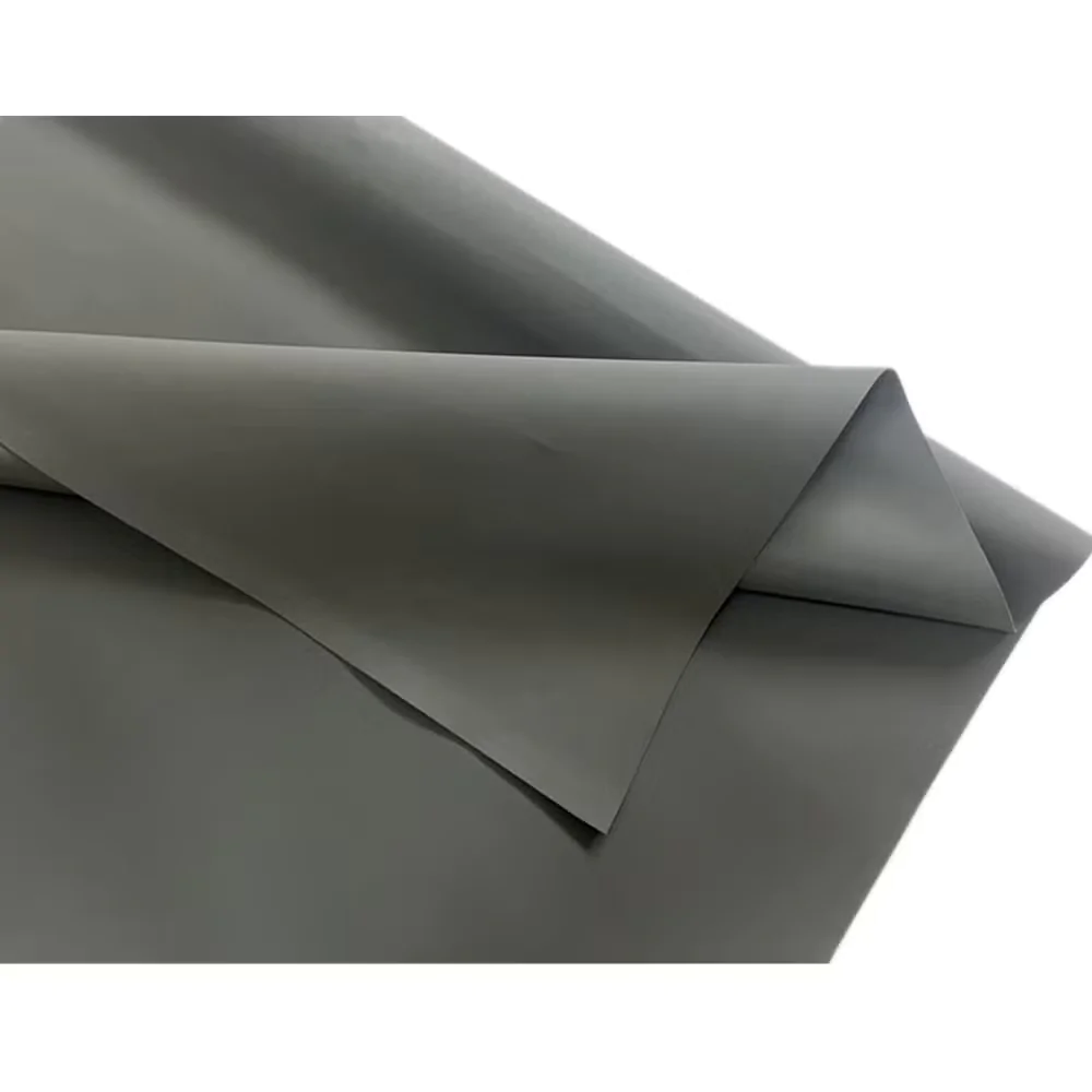 Close de uma pilha de folhas/tecidos de Hypalon na  cor cinza-oliva com acabamento suave. As folhas aparecem sobrepostas, com cantos retos e uma dobra acentuada na borda superior direita, criando sombras discretas. A textura é lisa, sem padrões visíveis. A composição foca em linhas diagonais formadas pelas bordas das camadas, destacando profundidade e contraste entre áreas claras e sombreadas