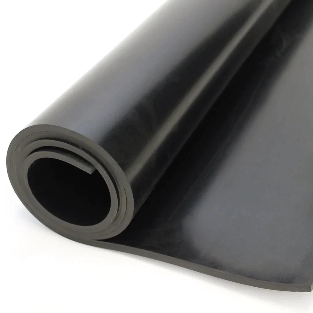 Rolo de borracha preta com espessura uniforme, parcialmente desenrolado sobre uma superfície branca. A peça forma um cilindro com interior oco visível, sugerindo um material de impermeabilização ou vedação, comum em aplicações industriais ou de construção. O brilho suave da superfície indica um acabamento liso e resistente.