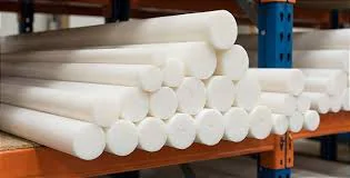 Esta imagem exibe uma pilha ordenada de tarugos cilíndricos de plástico branco, provavelmente nylon ou acetal, armazenados em uma prateleira de um armazém.